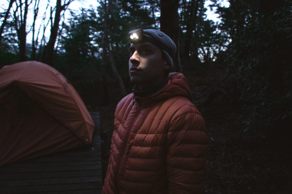 Man wearing a headlamp in a campsite